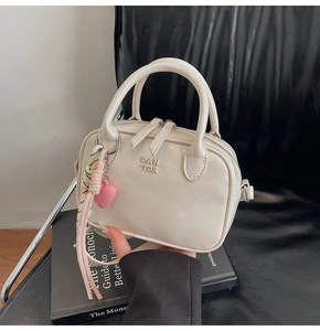 Détail du sac à main en cuir blanc cassé avec logo PAN 'TOR, double zip et pompon coeur