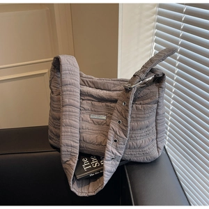 Detail of gray quilted shoulder bag with wave pattern and metallic adjustable strap