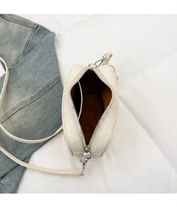 Dettaglio di una borsa a tracolla in pelle bianca grana con cerniera argento e fodera interna
