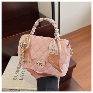 Detailed view of pale pink quilted box bag with silk scarf and metal chain strap