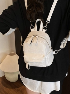Mini white backpack with snakeskin pattern and silver zippers shown on a model