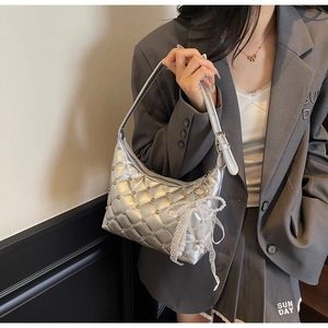 Détail du sac demi-lune argenté matelassé avec des clous et un nœud en dentelle perle