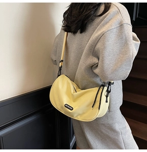 Detail view of yellow nylon crescent bag with adjustable strap and brand tag
