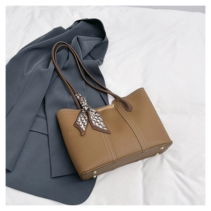 Detailed view of brown lychee-textured tote bag with white contrast stitching and scarf