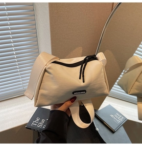 Détail du sac bandoulière en toile crème avec sangle large et fermeture éclair noire