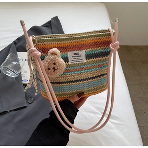 Detail showing colorful striped woven bucket bag texture with a cute brown plush bear charm