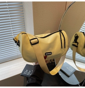 Detail of cream yellow nylon crossbody bag with adjustable wide strap and black zippers