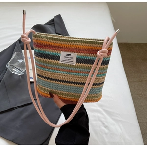 Close-up of woven bucket bag featuring colorful stripes and a pink knotted rope strap