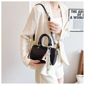 Detail of black pebbled leather Boston bag featuring gold hardware and a rainbow charm