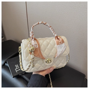 Detail of cream quilted leather box bag with gold twist lock and bear scarf handle decoration