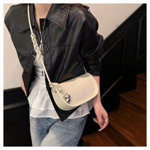 Détail d'un sac besace crème en cuir grainé avec bandoulière tressée sur modèle