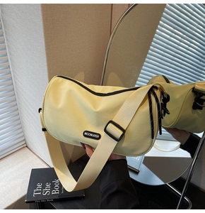 Detail of light yellow nylon crossbody bag with zipper, wide strap and woven rope accent