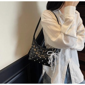 Détail du sac bandoulière matelassé noir avec clous diamantés et pendentif perle et nœud