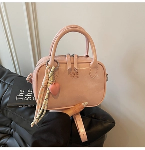 Détail du sac à bandoulière rose avec pendentif coeur et sangle tissée