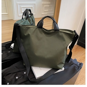 Detail of army green nylon tote bag with wide black strap and dual handles for crossbody use