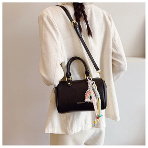 Close-up of black pebble leather Boston bag with a colorful rainbow rope charm detail