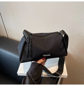 Détail du sac bandoulière en nylon noir avec fermetures éclair en corde tissée