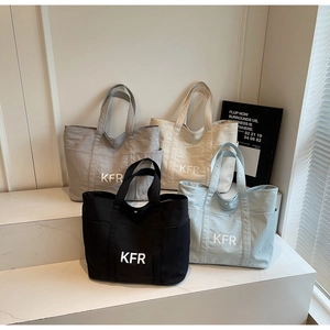 Detail view of four large canvas tote bags in grey, white, black and blue colors
