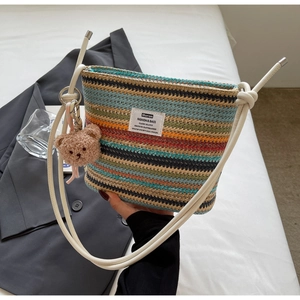 Detail of colorful woven bucket bag with long shoulder strap and cute bear charm