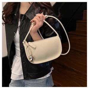 Détail du sac selle beige à texture grainée avec bandoulière nouée et cœur