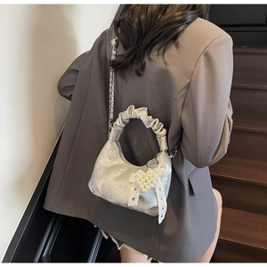 Silver hobo bag with pleated handle, pearl heart charm and lace bow on a model