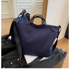 Detailed view of navy blue nylon tote bag with black straps on a lifestyle background