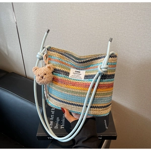Detailed weave of the colorful striped straw bucket bag with a cute plush bear charm