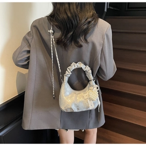 Detail of silver ruched handbag with vintage prints, pearl heart charm, and metal chain strap