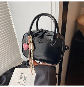 Détail du sac à main noir brillant avec logo PANTOR et breloque cœur rose élégante