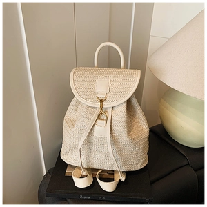 Detailed view of beige woven straw backpack featuring a metal hook clasp and fine texture