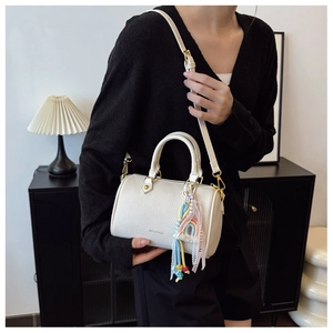Detail of cream Boston bag with lychee texture and colorful fringe tassel charm