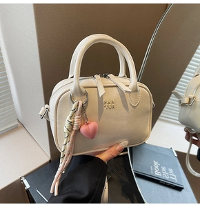Détail d'un sac à main blanc crème en cuir PU avec fermeture éclair et pendentif coloré