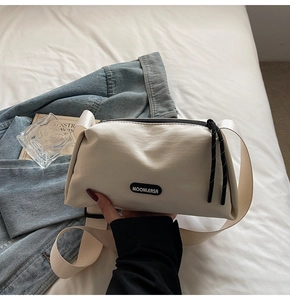 Gros plan du logo MOONLERSA sur le sac à bandoulière en toile beige à large sangle