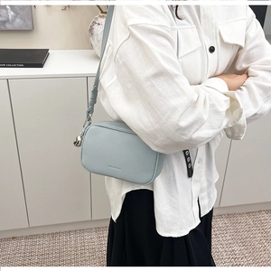 Dettaglio della pelle azzurra con motivo litchi e hardware argento sulla borsa a tracolla