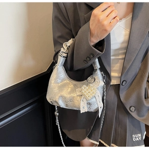 Detail of silver pleated handbag with numeric print, lace bow and pearl heart charm