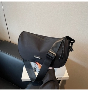 Detail of a black crescent crossbody bag with adjustable wide strap and logo detail