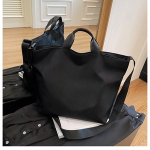 Detail of black waterproof nylon tote bag with dual handles and adjustable shoulder strap
