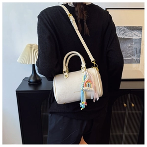 White lychee leather Boston bag with rainbow ribbon charm shown in an elegant home setting