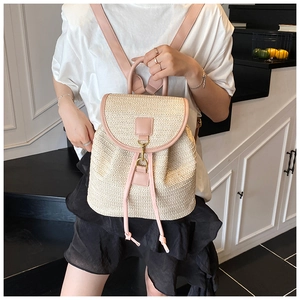 Detail of a woven straw backpack with pink leather accents and golden metal buckle
