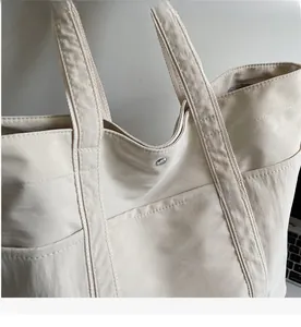 Detailed close-up of beige tote bag with snap button closure and reinforced stitching