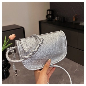 Détail du sac selle argenté montrant le cuir grainé et la poignée tressée chic