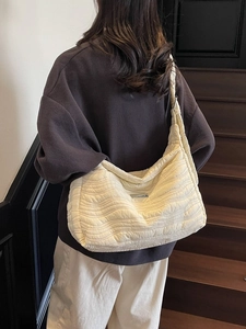 Chic beige quilted shoulder bag with wavy pleats and wide strap shown on a model