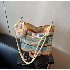 Close-up of colorful striped woven bucket bag with leather strap and cute bear charm