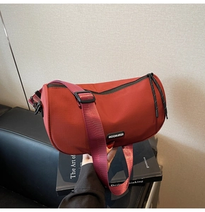 Close-up of red nylon half-moon crossbody bag with MOONLERSA logo and adjustable strap