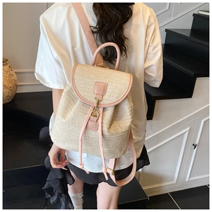 Detail view of woven straw backpack with pink leather straps and gold metal clasp closure