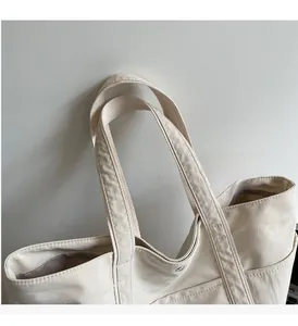 Detail of off-white canvas tote showing reinforced handles and precision double stitching