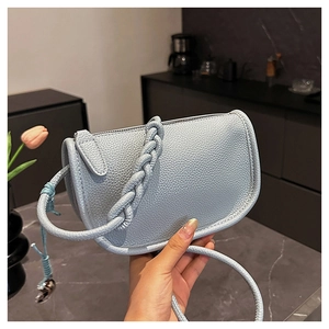 Gros plan du sac besace en cuir grainé bleu clair avec sa poignée tressée unique