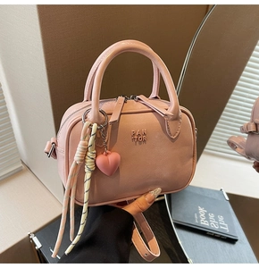 Détail du sac à main rose en similicuir avec lettrage embossé et pendentif en forme de cœur