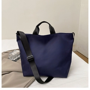 Detail of navy blue nylon tote bag with wide handles and adjustable strap for commuting