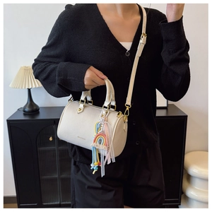 Detail of off-white lychee texture leather boston bag with rainbow charm and lace strap